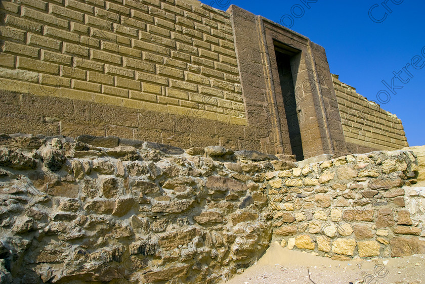 Karanis Southern Temple 6445EG07JHP 
 Karanis Kom Aushim Southern Temple Base Stones Gate Egyptian Construction was a city on the north eastern edge of the area known as Fayoum and dates from Ptolemaic times through to 500AD. Two Roman dated temples survive in reasonable state and the southern one whose front approach is illustrated in this photo is dedicated to the crocodile Gods of Pnepheros and Petesuchos. Many finds have been made especially of life in a residential area with houses scattered throughout the site and there is also a fine Roman bathhouse. A small museum now closed has ben replaced with an open air area with a selection of artefacts adjacent to the main walk to the temples. 
 Keywords: Egypt, Egyptian, Egyptology, upright, Karanis, Kom Aushim, el-Fayoum, Faiyum, Fayyum, Nero, Claudius, Vespasiun, Roman Emperors, South temple, outer, wall, construction, entrance, gate, foundations, gods, crocodile, dedicated, local, Pnepheros, Petesouchus, desert, sand