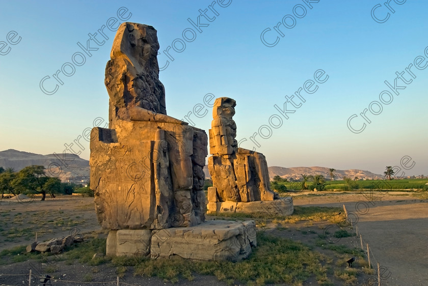 Colossi Memnon Luxor EG075314jhp 
 Colossi Memnon statues seated sunset Luxor West Bank hills Amenhotep Egyptian mortuary temple that are the most famous remains of his mortuary temple on the northern side of the approach road for the Valley of the Kings, Queens and all the other main West Bank sites. It is the visitors first site of major impact, not far from the main ticket office but is usually visited as a photo opportunity on leaving - recent excavations of the site are finding many hidden buildings and artefacts as well as defining the whole of the remains of the temple complex. 
 Keywords: Egypt, Egyptian, Luxor, West, Bank, Thebes, Theban, hills, fields, River, Nile, landscape, history, archaeology, ancient, Egyptology, Amenhotep, Amenophis, Pharaoh, Tiye, Queen, Mother, mortuary, temple, Colossi, Memnon, seated, statues, side, panels, Union, Upper, Lower, earthquake, damaged, repairs, Severus, sunset, glow, roadside, coachstop, excavations