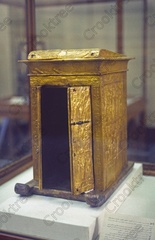 Tut Small Shrine EG11706JHP 
 Egyptian Museum Exhibit small gilded gold wooden shrine King Tut royal figurine is thought to have been stolen in antiquity from the Tomb of Tutankhamun and is now in the prime antiquities collection in Cairo taken during visits between 1994 and 1996 when photography was allowed albeit without flash and tripod. None is of studio quality, being handheld with existing, usually extremely poor light and using slide film, pushed Fuji 400asa to get a suitable aperture and shutter speed. Most of the photos are from the Tutankahum exhibits while the rest are items that interested me as I explored this wonderful and extensive collection, requiring many more hours if not days and is only hinted at during the usual one or two hour visit made on a package tour. 
 Keywords: Egypt, Cairo, Egyptian, Museum, Tutankhamun, shrine, gilded, empty, small, golden, Tut, collection, upright, ancient, antiquity, antiquities, exhibit