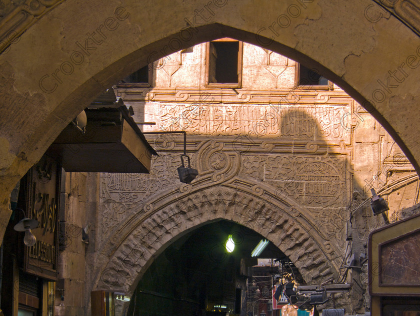 Cairo Khan al-Kalili EG072623jhp 
 Egypt Cairo Kan al-Kalili souk street old Arabic script carved historic part of this busy and often important site seeing stop-off for tourists to Egypt and offered as part of City Tour where many bargains can be picked up as part of that exotic shopping experience in an Arabic Bazaar. Bargaining is also part of the fun and is expected throughout so a new and often daunting experience for the traditional conservative British visitor. Better value can probably be obtained in Aswan or Luxor and certainly for those doing a Nile Cruise large, weighty or fragile items are best left to the last minute. 
 Keywords: Egypt, Egyptians, Cairo, cruise Arabic, script, carved, bargaining, tourism, tourists, landscape, capital, old, city, gates, Sultan, Qansuh, Fatimid, Kan al-Khalili, al-Kalili, souk, al-Badestan, maze, alleyways, alleys, shops, factories, bazaars, market, antiques, gold, jewellery, clothes, glass, leather, metal, wood, crafts, souvenirs, cafes, restaurants, sheeshas, trade, commercial, mosques, minaret, palm, trees, architecture, al-Azhar, Maydan, square, al-Hussein, Sayyidna, al-Husayn, building, 19C, Gothic