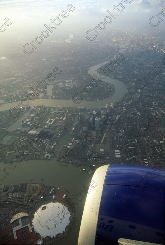 1919735jhp Aerial London Thames 
 Aerial view River Thames Canary Wharf O2 engine buildings distance London domestic flight from Aberdeen to London and on this occasion we circled for several minutes in a holding pattern before landing in a December late afternoon arrival at Heathrow. This was an overnight stay in the City to attend the BAPLA AGM and being able to pick daytime flights meant a rare chance to photograph from the plane. 
 Keywords: Britain, London, UK, city, Thames, Heathrow, river, bridges, Eye, 02, round, tented, building, venue, events, Canary, Wharf, sky, flying, winter, afternoon, plane, window, polarised, upright, landscape, BMI, British Airways, Boeing, 737, domestic, circling, approach, holding, pattern, sky, blue, clouds, white, sun, orange, red, pink, brown, salmon, yellow, panoramic, dramatic, spectacular, 2002, Velvia, 35mm, slide, film, scanned, scan