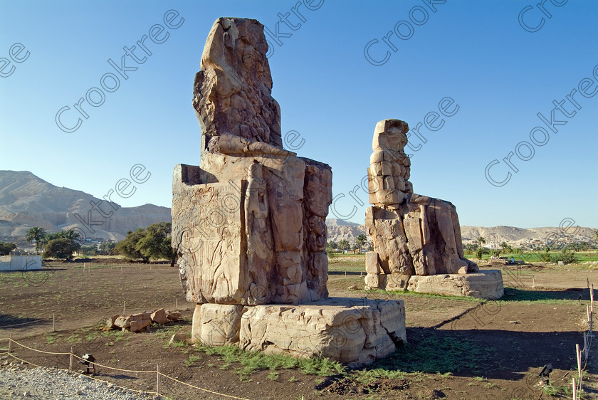 Colossi of Memnon EG051936JHP 
 Colossi Memnon West Bank River Nile Luxor two ruined seated statues of Amenhotep 111 that are the most famous remains of his mortuary temple on the northern side of the approach road for the Valley of the Kings, Queens and all the other main West Bank sites. It is the visitors’ first site of major impact, not far from the main ticket office but is usually visited as a photo opportunity on leaving - recent excavations of the site are finding many hidden buildings and artefacts. see Victorian collection for similiar viewpoint. 
 Keywords: Egypt, Egyptian, Luxor, West Bank, Thebes, Theban, hills, River Nile, Colossi of Memnon, seated, statues, Amenhotep, Pharaoh, side, relief, union, upper, lower, Hapi, tying, lotus, papyrus, landscape, history, archaeology, ancient, then, now, Victorian, Beato, Egyptology, temple, roadside, coachstop, excavations, farmland