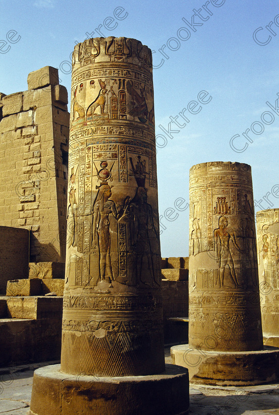 Kom Ombo EG204312jhp 
 Kom Ombo Temple Nile Egyptian hieroglyphs Hathor Ptolemy Horus painted carvings of this beautiful ruined temple just north of Aswan and a regular visit on all Nile Cruises, was principally built by Ptolemy V of Silsilah sandstone. Dedicated to two Gods  Sobek, the crocodile and Horus, the falcon and although it has been damaged over the years, mainly through slipping into the River Nile and some structural damage owing to earthquakes, there are still some wonderful colourful reliefs of the most detailed and delicate style. This trip was special for me in that I got special permission to climb up the back of the temple on the hill behind and match a view I had on a Victorian albumen print; the local Police Chief had to be involved and thanks to a good Kuoni Guide he agreed for me to be accompanied by a policemen as security was still a big thing after the 1997 attacks at Luxor. Unfortunately in the excitement I had forgot to adjust my ASA rating for Velvia and took the photos based on 400ASA-the film maws later pushed to 200asa so there is some increase in grain structure, not a feature of Velvia generally. On this visit some cleaning and restoration was being done to the many painted bas reliefs on the columns-hence the scaffolding and the sun umbrella but the bonus was the reliefs looked particularly vibrant. The time of day also meant some of the museum blocks with deep cut carvings were ideal to photograph as the shadows gave greater emphasis to the excellent cut marks of some iconic hieroglyphic symbols. 
 Keywords: Egypt, East Bank, River Nile, Kom Ombo, Temple, summer, morning, hypostyle hall, pylon, columns, bas, reliefs, restoration, cleaning, conservation, coloured, colored, colours, colors, Silsilah, sandstone, landscape, upright, history, archaeology, ancient, Egyptian, Egyptology, crocodiles, Ptolemaic, Ptolemy, Horus, Haroeris, Harwer, Sobek, Hathor, carvings, detailed, delicate, beautiful, fine, Velvia, slide, film, scans, scan, scanned, 35mm, Nikon, FM, manual, July, 2000
