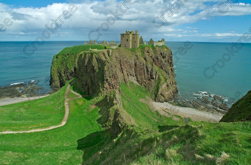 Dunnottar Castle Scotland S0798JHP 
 Dunnottar Castle south of Stonehaven on the Aberdeenshire North Sea coast viewed from the cliffs and showing its spectacular situation and stragetic location as a fortress steeped in Scottish history. 
 Keywords: Scotland Scottish Aberdeenshire North east sea Stonehaven Dunnottar Castle landscape panorama panoramic arched window stonework weathered erosion tourism visitors spectacular coast sea coastal cliffs grass green blue sky white clouds sunny rocks headland bay Haven conglomerate pudding stone Dun Fother Benholm Lodging keep tower curtain portcullis vaulted pends 14th century Marischal storehouse smithy bakery brewery stables guardhouse quadrangle well mansion chambers chapel Whigs Vault prison dungeon siege Honours jewels Covenanters exhibition