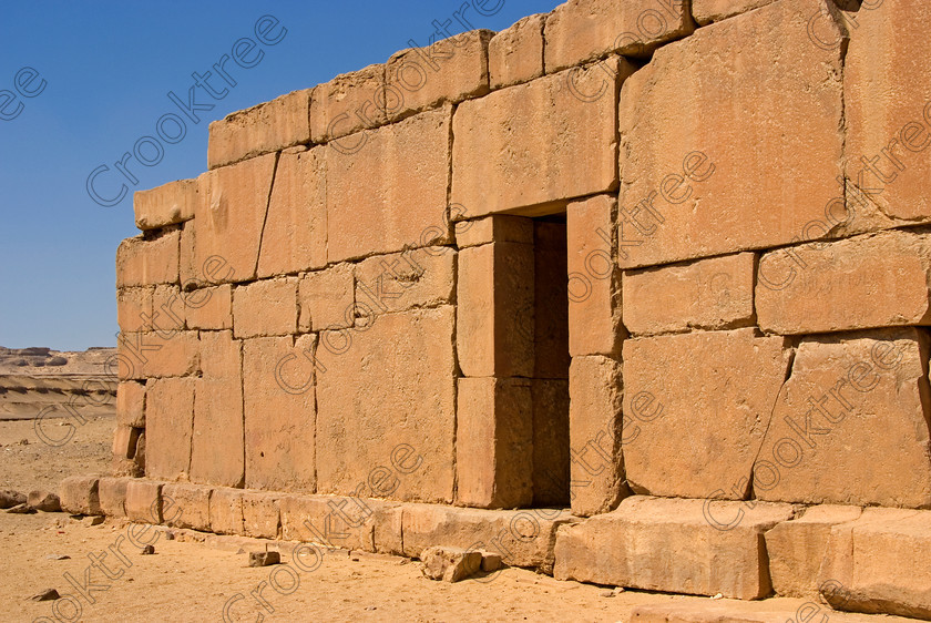 Qasr al-Saghah Temple 6600EG07JHP 
 Qasr al-Saghah Ancient Egypt Desert Unfinished Temple Workers small late 12th century Egyptian worker's temple, uninscribed near the Gebel el-Qatrani worker's town servicing the basalt mines to the west of Lake Qarun and accessible only by 4x4 on specialist tours of Egypt. It is constructed of dark brown calciferous sandstone with seven cult shrines facing a common offering table room with the probable front of the temple never finished. 
 Keywords: Egypt, Egyptian, Egyptology, al-Siba, Qasr el-Sagha, al-Saghah, Es-Saghah, Temple, door, entrance, seven, cult, shrines, crypt, offering, table, room, Sobek, archaeology, ancient, history, landscape, desert, safari, calciferous, sandstone, blocks, huge, sand, blistering, heat, sun, blue, sky, eroded, stones, foreground, hills, stratified, erosion