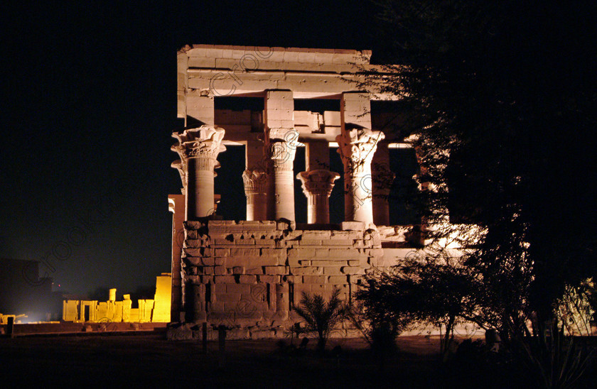 Aswan Philae Light Show EG02946jhp 
 Philae Light Show Aswan Egypt Trajan Kiosk color lit night in which, during the first section, spectators walk through the temple with areas highlighted at each stop but the time to take photographs is limited. The second part of the evening as illustrated in this photo is seated and photography is very easy, a tripod is permitted and necessary for time exposures to be made as flash on cameras is almost pointless and more of a nuisance for other viewers. This Sound & Light Show is perhaps the most spiritual of those shown at other centres especially with the trip at night by boat to the island and the peacefulness that naturally surrounds this location. 
 Keywords: Egypt, Aswan, River, Nile, Nubia, Agilkia, Philae, Temple, landscape, Trajan, Kiosk, columns, floral, capitals, Roman, Island, Sound, Light, Son, Lumiere, surreal, experience, spectacular, fantasy, dramatic, colours, colors, colourful, colorful, history, antiquity, ancient, Egyptian, walk, through, sitting, dark, night, stars, holiday, travel, tourists, tourism, boat, water, Egyptology, 2002, Fuji, S2, DSLR