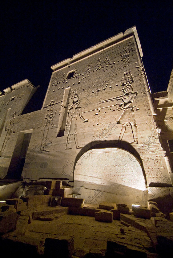 Philae Light Show EG052889JHP 
 Philae Temple Light Show Ptolemy Pylon Face Carvings Etched Shadows Stele at Aswan in which, during the first section, spectators walk through the temple with areas highlighted at each stop but the time to take photographs is limited. The second part of the evening is seated and photography is very easy, a tripod is permitted and necessary for time exposures to be made as flash on cameras is almost pointless and more of a nuisance for other viewers. This Sound & Light Show is perhaps the most spiritual of those shown at other centres especially with the trip at night by boat to the island and the peacefulness that naturally surrounds this location. 
 Keywords: Egypt, Egyptian, Aswan, River Nile, Agilkia Island, island, Philae, Horus, temple, light, sound, show, upright, second, pylon, stele, Ptolemy, Philometer, Son, Lumiere, spectacular, fantasy, dramatic, night, dark, stars, colours, colors, colourful, colorful, spiritual, surreal