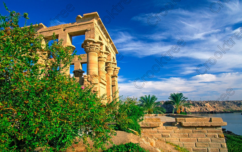 Trajan Kiosk Philae EG022311JHP 
 Philae Temple Trajan Kiosk Nile Clouds Cirrus Dramatic Agilkia Island Egypt home of the Goddess Isis was established late in the history of Egypt being mainly Ptolemaic, eventually closing as a religious site around 550AD and being located on an island had remained remarkably untouched. Being relocated onto the Island of Agilkia on the River Nile near Aswan, to save it being flooded after the completion of the High Dam, it is perhaps one of the loveliest and most complete classic Egyptian temples to visit with a peaceful spirituality lacking in many of the land based sites. 
 Keywords: Egypt, Aswan, River Nile, Nubia, Philae Temple, island, Trajan, kiosk, waterfront, landscape, history, ancient, Egyptian, antiquity, archaeology, Egyptology, Agilkia Island, flowers, oleander, palm, trees, water, cirrus, clouds, slide, scanned