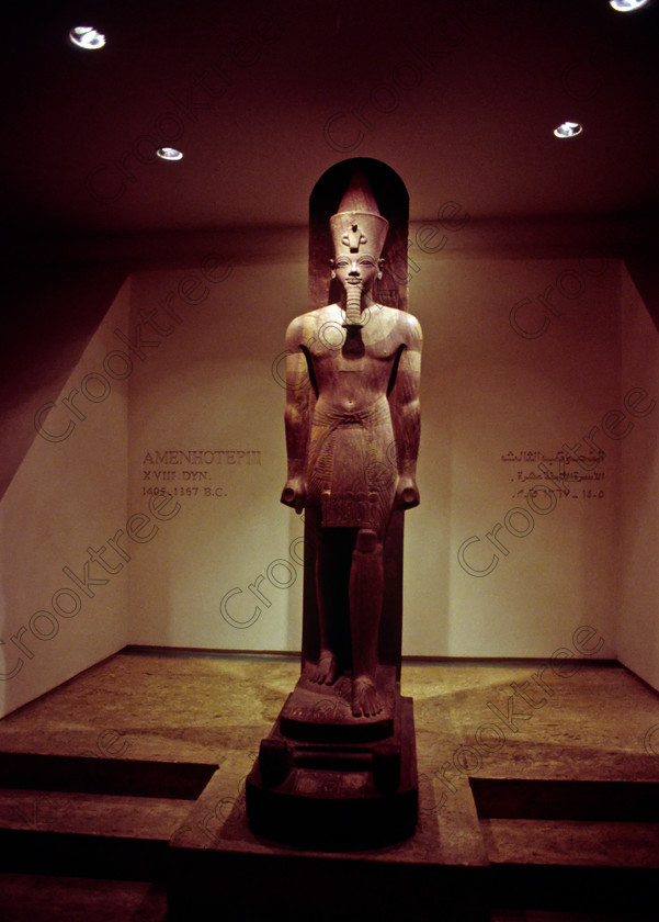 Luxor Amenhotep Standing EG9620920JHP 
 Egyptian Museum Luxor Library Photos Cache Red Quartzite Statue Amenhotep was photographed inside this modern building on the waterfront of the River Nile with its fascinating collection covering the extensive history of ancient Egypt including items from the Tomb of Tutankahum. These particular exhibits are in an annex displaying statues discovered in 1989 in a storage pit and called The Luxor Temple Cachette of which the red quartzite life size statue of Amenhotep 111 is one of the finest pieces of carving yet found in Egypt. This photo was taken in 1996 when you could pay to take photographs but not use a tripod, now not allowed at all, and I used Kodak 5042 Tungsten Slide film which still meant hand holding was at the extremes of useful photography in low light conditions. 
 Keywords: Egypt, Egyptian, Luxor, East, Bank, River, Nile, Museum, Cache, Cachette, Temple, Interior, Statue, landscape, history, archaeology, Egyptology, exhibit, Pharaoh, Amenhotep, Amenophis, standing, complete, red, quartzite, carved