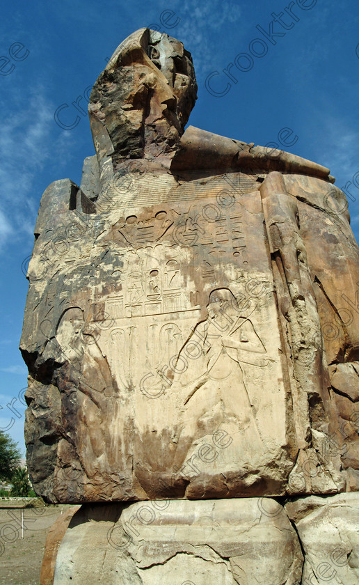 Colossi of Memnon EG020150jhp 
 Colossi Memnon West Bank Luxor Napi carving seated statues Amenhotep 111 that are the most famous remains of his mortuary temple on the northern side of the approach road for the Valley of the Kings, Queens and all the other main West Bank sites. It is the visitors first site of major impact, not far from the main ticket office but is usually visited as a photo opportunity on leaving - recent excavations of the site are finding many hidden buildings and artefacts. see Victorian collection for similar viewpoint. 
 Keywords: Egypt, Egyptian, Luxor, West Bank, Thebes, Theban, hills, River Nile, Colossi of Memnon, seated, statues, Amenhotep, Pharaoh, side, relief, union, upper, lower, Hapi, tying, lotus, papyrus, upright, history, archaeology, ancient, then, now, Victorian, Beato, Egyptology, temple, roadside, coachstop, excavations, farmland