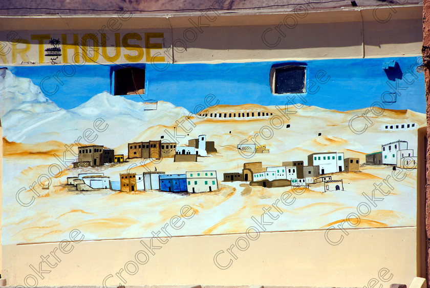 Old Qurna New Art EG075729JHP 
 Modern Egyptian Art House Mural Old Qurna Village Luxor Modern Photo interspersed with the Tombs of the Nobles is undergoing a major modernisation programme with the houses being removed, occupants relocated and the entrances to the various tombs made more accessible and a feel is captured in this mural on the side of an arthouse. Obviously a programme without some pain and opposition especially from locals who have lived in the area and over the tombs for generations but part of the necessary management and control of these irreplaceable ancient sites and the artefacts contained therein. 
 Keywords: Egypt, Egyptian, ancient, Luxor, Tombs, Nobles, Thebes, River Nile, West Bank, Old Qurna, Sheikh Abd’el-Qurna, upright, landscape, village, nostalgia, art, modern, mural, modernisation, removal, houses, clearances, relocation, preservation