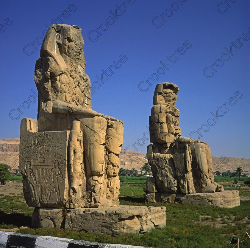 Colossi Memnon EG01332jhp 
 Colossi Memnon Egypt side view two seated statues square 6x6 format slides Amenhotep 111 that are the most famous remains of his mortuary temple on the northern side of the approach road for the Valley of the Kings, Queens and all the other main West Bank sites. It is the visitors first site of major impact, not far from the main ticket office but is usually visited as a photo opportunity on leaving - recent excavations of the site are finding many hidden buildings and artefacts. 
 Keywords: Egypt, Egyptian, Luxor, West Bank, Thebes, Theban, hills, River Nile, Colossi, Memnon, seated, statues, Amenhotep, Pharaoh, side, relief, union, upper, lower, Hapi, tying, lotus, papyrus, landscape, history, archaeology, ancient, then, now, Victorian, Beato, Egyptology, temple, roadside, coachstop, excavations, farmland, 2001, October, Fuji, RVP, Velvia, slide, medium, format, 6x6, square, 120, transparency, scanned, scan, Yashica, Mat 124G
