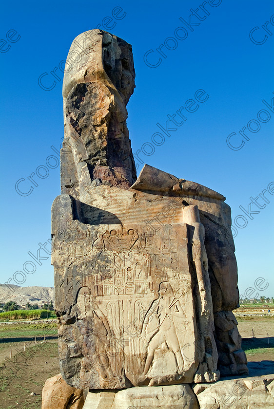 Colossi of Memnon EG051933JHP 
 Colossi Memnon Egyptian West Bank Luxor ruined seated statue Amenhotep 111 that are the most famous remains of his mortuary temple on the northern side of the approach road for the Valley of the Kings, Queens and all the other main West Bank sites. It is the visitors’ first site of major impact, not far from the main ticket office but is usually visited as a photo opportunity on leaving - recent excavations of the site are finding many hidden buildings and artefacts. 
 Keywords: Egypt, Egyptian, Luxor, West Bank, Thebes, Theban, hills, River Nile, Colossi of Memnon, seated, statues, Amenhotep, Pharaoh, side, relief, union, upper, lower, Hapi, tying, papyrus, lotus, upright, history, archaeology, ancient, Egyptology, temple, roadside, coachstop, excavations, farmland