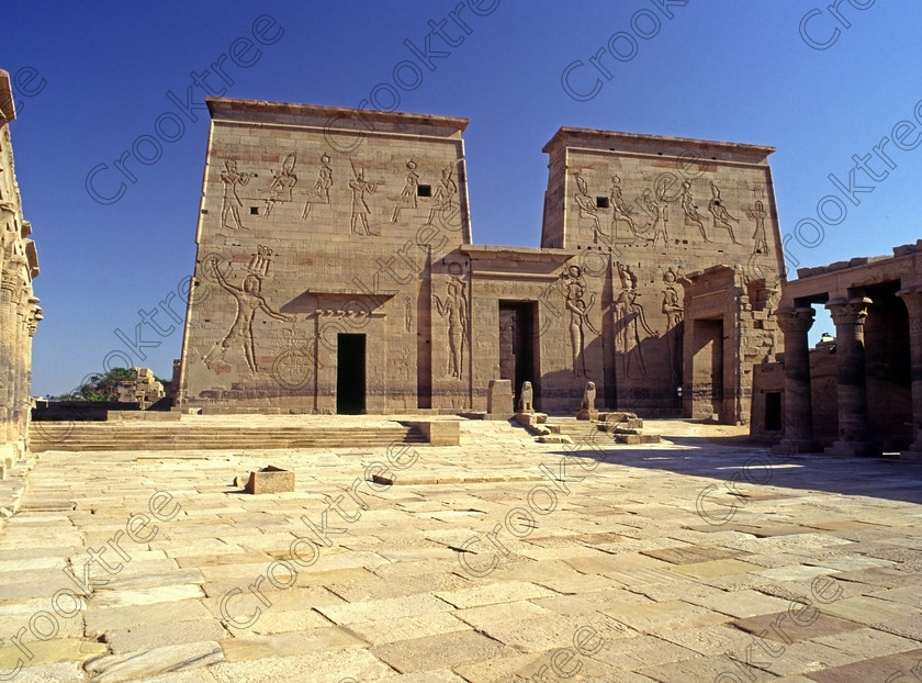 Courtyard Philae Temple EG9410411jhp 
 Philae Temple courtyard Ancient Egyptian Isis pylon columns carvings Gods Aswan island was established late in the history of Egypt being mainly Ptolemaic, eventually closing as a religious site around 550AD and being located on an island had remained remarkably untouched. Being relocated onto the Island of Agilkia on the River Nile near Aswan, to save it being flooded after the completion of the High Dam, it is perhaps one of the loveliest and most complete classic Egyptian temples to visit with a peaceful spirituality lacking in many of the land based sites. 
 Keywords: Egypt, Aswan, River, Aswan, Nile, Nubia, Philae Temple, island, pylon, carvings, face, courtyard, landscape, history, ancient, Egyptian, antiquity, archaeology, Egyptology, Agilkia, Island, motorboat, water, scanned, scan, 645, slide, film, transparency, Bronica, ETRSi, 1994