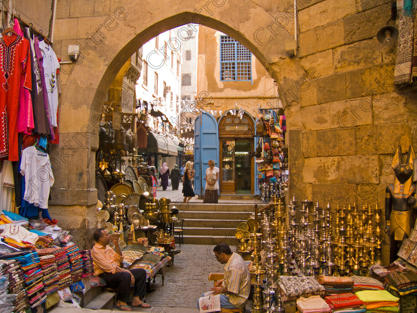Cairo Khan al-Kalili EG072634jhp 
 Egypt Cairo Kan al-Khalili souk arch historic alleyway tourists owners cotton brass goods in a busy and often important site seeing stop-off for tourists to Egypt and offered as part of City Tour where many bargains can be picked up as part of that exotic shopping experience in an Arabic Bazaar. Bargaining is also part of the fun and is expected throughout so a new and often daunting experience for the traditional conservative British visitor. Better value can probably be obtained in Aswan or Luxor and certainly for those doing a Nile Cruise large, weighty or fragile items are best left to the last minute. 
 Keywords: Egypt, Egyptians, Cairo, cruise Arabic, bargaining, tourism, tourists, landscape, capital, old, city, gates, Sultan, Qansuh, Fatimid, Kan al-Khalili, al-Kalili, souk, al-Badestan, maze, alleyways, alleys, shops, factories, bazaars, market, antiques, gold, jewellery, clothes, glass, leather, metal, wood, crafts, souvenirs, cafes, restaurants, sheeshas, trade, commercial, mosques, minaret, palm, trees, architecture, arch, al-Azhar, Maydan, square, al-Hussein, Sayyidna, al-Husayn, building, 19C, Gothic, historic