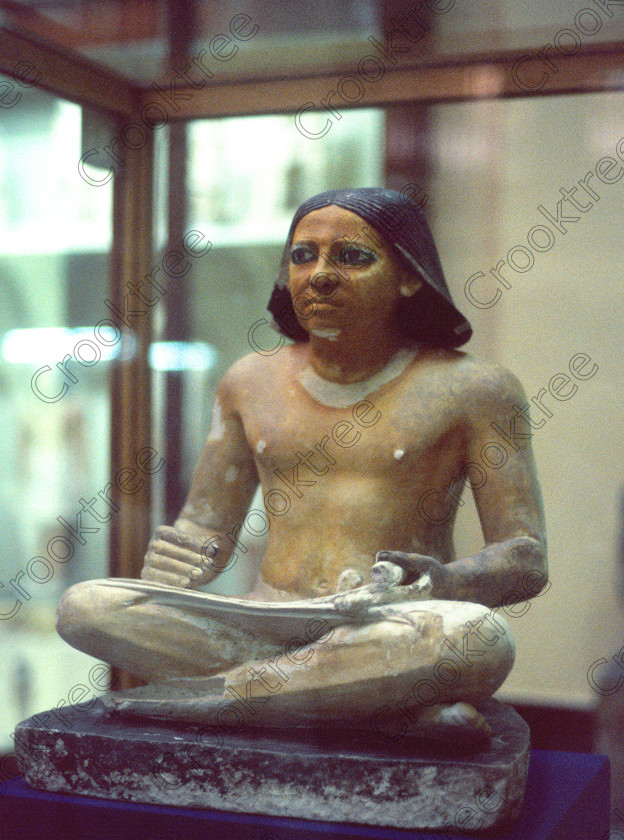 Squatting Scribe EG11822JHP 
 Egyptian Museum Cairo Exhibit iconic nameless Saqqara scribe thoughtful pose with cane pen and papyrus in the prime antiquities collection in Cairo taken during visits between 1994 and 1996 when photography was allowed albeit without flash and tripod. None is of studio quality, being handheld with existing, usually extremely poor light and using slide film, pushed Fuji 400asa to get a suitable aperture and shutter speed. Most of the photos are from the Tutankahum exhibits while the rest are items that interested me as I explored this wonderful and extensive collection, requiring many more hours if not days and is only hinted at during the usual one or two hour visit made on a package tour. 
 Keywords: Egypt, Cairo, Egyptian, Museum, scribe, iconic, pose, seated, squatting, pen, papyrus, nameless, collection, landscape, painted, limestone, Saqqara, ancient, antiquity, antiquities, exhibit