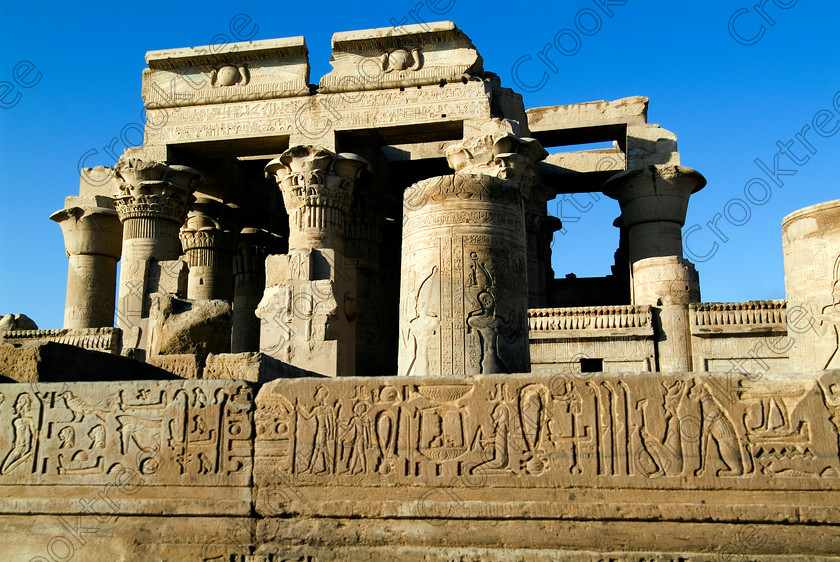 Kom Ombo Temple EG052516JHP 
 Kom Ombo Ptolemaic Temple Forecourt Hypostyle Hall Photograph Carvings Egypt on the River Nile just north of Aswan and a regular visit on all Nile Cruises, was principally built by Ptolemy V of Silsilah sandstone. Dedicated to two Gods – Sobek, the crocodile and Horus, the falcon and although it has been damaged over the years, mainly through slipping into the River Nile and some structural damage owing to earthquakes, there are still some wonderful colourful reliefs of the most detailed and delicate style. 
 Keywords: Egypt, East Bank, River Nile, Kom Ombo, Temple, hypostyle hall, lintel, solar, disc, forecourt, wall, detail, netcher, bastet, hieroglyphs, columns, bas reliefs, coloured, colored, colours, colors, Silsilah, sandstone, landscape, history, archaeology, ancient, Egyptian, Egyptology, crocodiles, Ptolemaic, Ptolemy, carvings, detailed, delicate, beautiful, fine