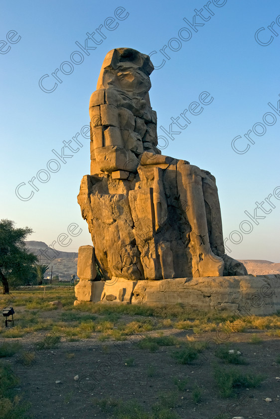 Colossi Memnon Luxor EG075304jhp 
 Colossi Memnon statue seated Amenhotep Queen Tiye Egyptian mortuary temple that are the most famous remains of his mortuary temple on the northern side of the approach road for the Valley of the Kings, Queens and all the other main West Bank sites. It is the visitors first site of major impact, not far from the main ticket office but is usually visited as a photo opportunity on leaving - recent excavations of the site are finding many hidden buildings and artefacts as well as defining the whole of the remains of the temple complex. 
 Keywords: Egypt, Egyptian, Luxor, West, Bank, Thebes, Theban, hills, fields, River, Nile, upright, history, archaeology, ancient, Egyptology, Amenhotep, Amenophis, Pharaoh, Tiye, Queen, Mother, mortuary, temple, Colossi, Memnon, seated, statue, side, panels, Union, Upper, Lower, earthquake, damaged, repairs, Severus, sunset, glow, roadside, coachstop, excavations