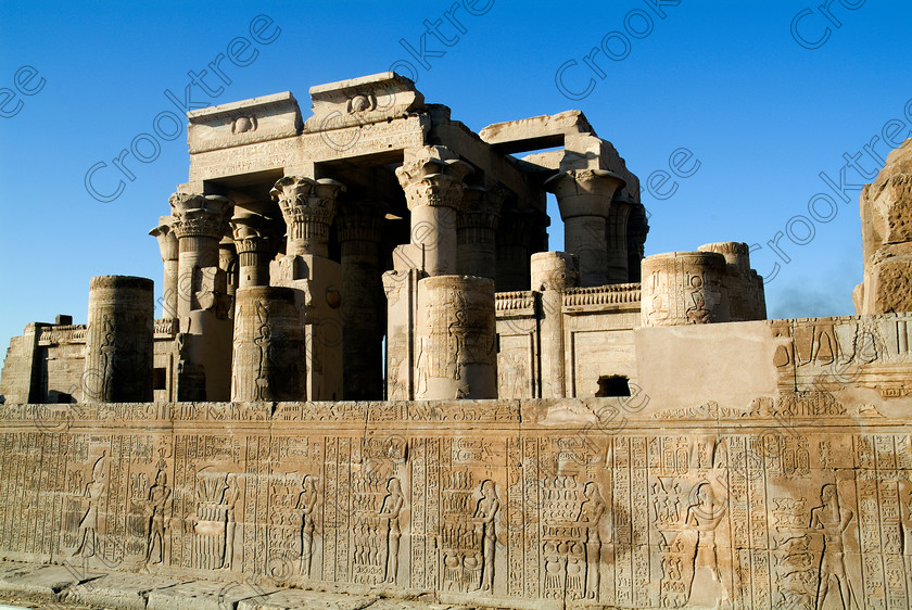 Kom Ombo Temple EG052504JHP 
 Kom Ombo Egyptian Temple Hypostyle Hall Photo Forecourt Reliefs Offering Scene on the River Nile just north of Aswan and a regular visit on all Nile Cruises, was principally built by Ptolemy V of Silsilah sandstone. Dedicated to two Gods – Sobek, the crocodile and Horus, the falcon and although it has been damaged over the years, mainly through slipping into the River Nile and some structural damage owing to earthquakes, there are still some wonderful colourful reliefs of the most detailed and delicate style. 
 Keywords: Egypt, East Bank, River Nile, Kom Ombo, Temple, hypostyle hall, columns, forecourt, wall, hieroglyphs, bas reliefs, coloured, colored, colours, colors, Silsilah, sandstone, landscape, history, archaeology, ancient, Egyptian, Egyptology, Ptolemaic, Ptolemy, Horus, Haroeris, Harwer, Sobek, Hathor, carvings, detailed, delicate, beautiful, fine