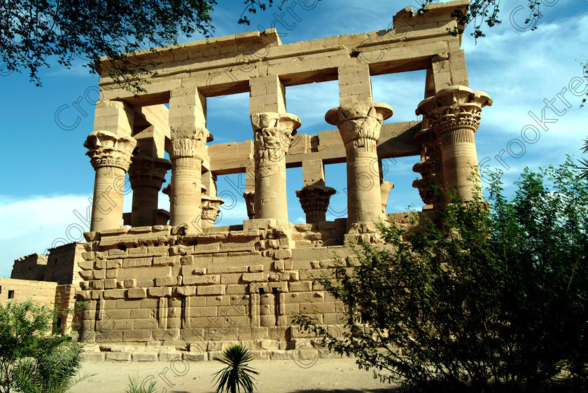 Philae Trajans Kiosk EG02513JHP 
 Egypt Aswan Philae Temple Trajan Kiosk Trees Oleander Capitals Floral home of the Goddess Isis was established late in the history of Egypt being mainly Ptolemaic, eventually closing as a religious site around 550AD and being located on an island had remained remarkably untouched. Being relocated onto the Island of Agilkia on the River Nile near Aswan, to save it being flooded after the completion of the High Dam, it is perhaps one of the loveliest and most complete classic Egyptian temples to visit with a peaceful spirituality lacking in many of the land based sites. 
 Keywords: Egypt, Aswan, River Nile, Nubia, Philae Temple, island, pylon, Trajan, kiosk, capitals, floral, landscape, history, ancient, Egyptian, antiquity, archaeology, Egyptology, Agilkia Island, tree, shrubs