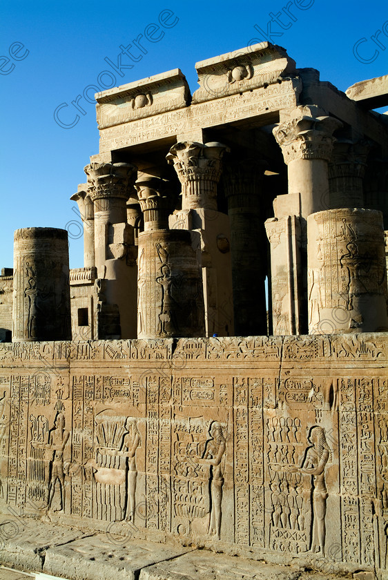 Kom Ombo Temple EG052505JHP 
 Kom Ombo Temple Hall Solar Disc Lintel Roof Floral Capitals Carvings Forecourt on the River Nile just north of Aswan and a regular visit on all Nile Cruises, was principally built by Ptolemy V of Silsilah sandstone. Dedicated to two Gods – Sobek, the crocodile and Horus, the falcon and although it has been damaged over the years, mainly through slipping into the River Nile and some structural damage owing to earthquakes, there are still some wonderful colourful reliefs of the most detailed and delicate style. 
 Keywords: Egypt, East Bank, River Nile, Kom Ombo, Temple, hypostyle hall, lintel, solar, disc, columns, bas reliefs, wall, hieroglyphs, cartouches, coloured, colored, colours, colors, Silsilah, sandstone, upright, history, archaeology, ancient, Egyptian, Egyptology, crocodiles, Ptolemaic, Ptolemy, Horus, Haroeris, Harwer, Sobek, Hathor, carvings, detailed, delicate, beautiful, fine