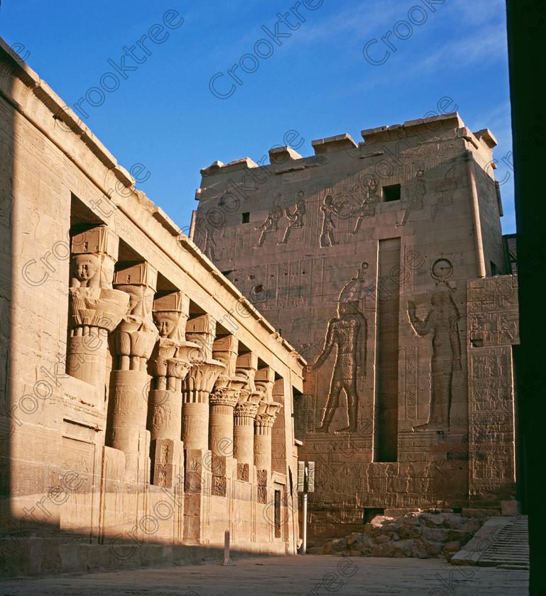 Philae Mammisi SS981812JHP 
 Ancient Philae Egyptian Temple Mamissi Birth House Pylon Courtyard Photo home of the Goddess Isis was established late in the history of Egypt being mainly Ptolemaic, eventually closing as a religious site around 550AD and being located on an island had remained remarkably untouched. Being relocated onto the Island of Agilkia on the River Nile near Aswan, to save it being flooded after the completion of the High Dam, it is perhaps one of the loveliest and most complete classic Egyptian temples to visit with a peaceful spirituality lacking in many of the land based sites. 
 Keywords: Egypt, Aswan, River Nile, Nubia, Philae Temple, island, pylon, second, mammisi, birth house, columns, capitals, Ptolemy, Isis, Hathor, face, square, history, ancient, Egyptian, antiquity, archaeology, Egyptology, Agilkia Island, transparency, scanned