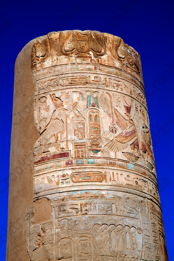 Kom Ombo Painted Column EG052460JHP 
 Egyptian Kom Ombo Ptolemaic Temple Painted Horus Vulture Nekhbet Photo Column on the River Nile just north of Aswan and a regular visit on all Nile Cruises, was principally built by Ptolemy V of Silsilah sandstone. Dedicated to two Gods – Sobek, the crocodile and Horus, the falcon and although it has been damaged over the years, mainly through slipping into the River Nile and some structural damage owing to earthquakes, there are still some wonderful colourful reliefs of the most detailed and delicate style. 
 Keywords: Egypt, East Bank, River Nile, Kom Ombo, Temple, hypostyle hall, pylon, columns, bas reliefs, coloured, colored, colours, colors, Silsilah, sandstone, upright, cartouche, hieroglyphs, history, archaeology, ancient, Egyptian, Egyptology, Ptolemaic, Ptolemy, Horus, Haroeris, Harwer, wadjet, serpent, winged, vulture, double crown, pschent, carvings, detailed, delicate, beautiful, fine
