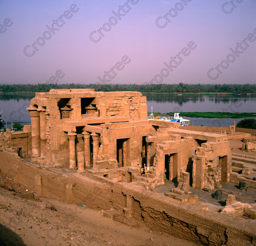 Kom Ombo EG004012JHP 
 Kom Ombo Temple High View Unusual Rare Rear Hall Wall Nile Background on the River Nile just north of Aswan and a regular visit on all Nile Cruises. This is an unusual viewpoint and required special permission and I was accompanied to be allowed to photograph outside the temple enclosure wall. 
 Keywords: Egypt, East Bank, River Nile, Kom Ombo, Temple, hypostyle hall, enclosure wall, mudbrick, hill, above, square, cruiseboat, high, view, history, archaeology, ancient, Egyptian, Egyptology, crocodiles, Ptolemaic, Horus, Haroeris, Harwer, Sobek, Hathor, transparency, scan