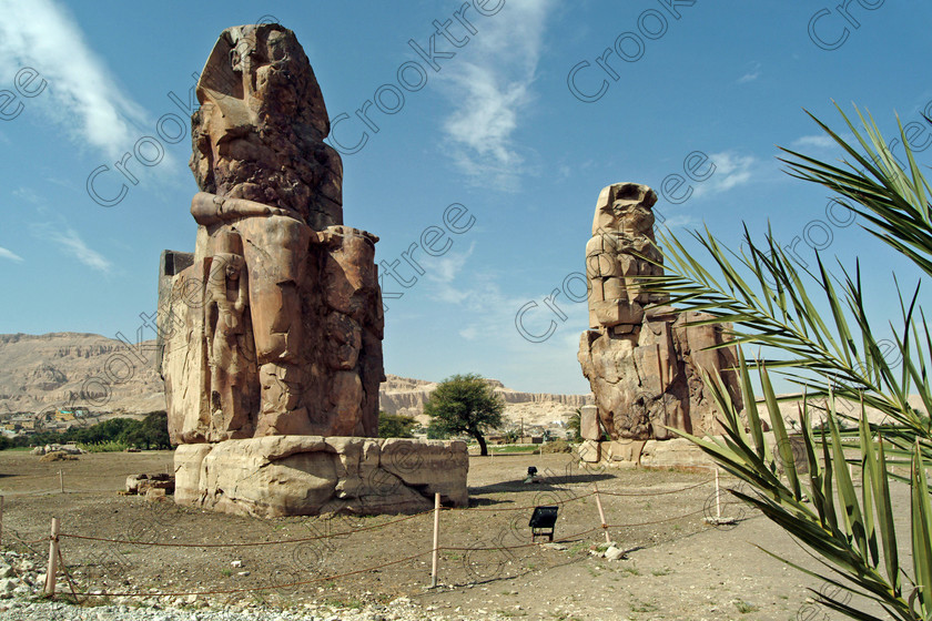 Colossi of Memnon EG020145jhp 
 Colossi Memnon West Bank ancient Egypt Luxor two ruined seated statues of Amenhotep 111 that are the most famous remains of his mortuary temple on the northern side of the approach road for the Valley of the Kings, Queens and all the other main West Bank sites. It is the visitors first site of major impact, not far from the main ticket office but is usually visited as a photo opportunity on leaving - recent excavations of the site are finding many hidden buildings and artefacts. see Victorian collection for similar viewpoint. 
 Keywords: Egypt, Egyptian, Luxor, West Bank, Thebes, Theban, hills, River, Nile, Colossi of Memnon, Colossi, Memnon, seated, statues, Amenhotep, Pharaoh, side, relief, union, upper, lower, Hapi, tying, lotus, papyrus, landscape, history, archaeology, ancient, then, now, Victorian, Beato, Egyptology, temple, roadside, coachstop, excavations, farmland