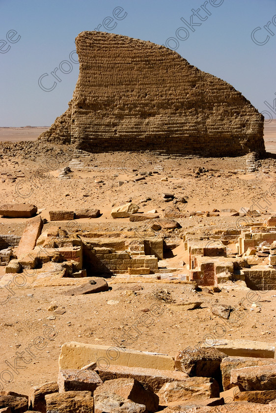 Soknopaiou Nesos Temple 6565EG07JHP 
 Soknopaiou Nesos Ruins Dimyah al-Siba Ptolemaic town Mudbrick Walls Desert dating through to Roman times built by the shores of Lake Qarun or Moeris, with a substantial mudbrick enclosure wall partially buried surrounding the remains of a temple, in the centre of this photo, dedicated to Soknopaios, a form of the crocodile God Sobek. It is located in the western desert south of Cairo and is accessed by 4x4 from Faiyum and is often part of a desert trip including Qasr al-Saghah Temple. 
 Keywords: Egypt, Egyptian, Egyptology, el-Fayoum, Fayyum, Fayum, Lake Qarun, Moeris, Soknopaiou Nesos, island, Dimyah al-Siba, archaeology, ancient, history, landscape, digital, desert, Ptolemaic, Ptolemy 11 Philadelphus, Septimius Severus, temple, Suchos, Soknopaios, Sobek, processional, way, mudbrick, enclosure, walls, layering, pan, bedding, hot, sand, blistering, heat, sun, blue, sky, angle, eroded, stones