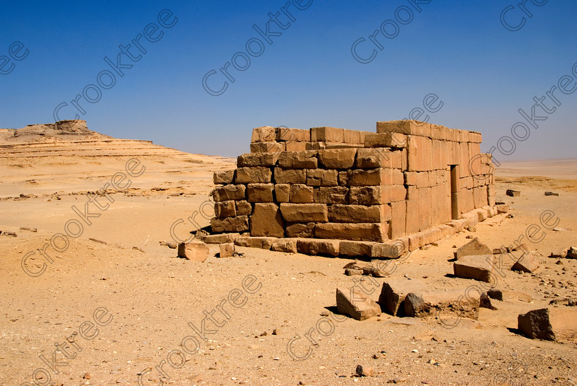 Qasr al-Saghah Temple 6591EG07JHP 
 Qasr al-Saghah Desert Temple Ancient Egyptian Sand Hot Hill Isolated small late 12th century Egyptian worker's temple, unfinished and uninscribed near the Gebel el-Qatrani worker’s town servicing the basalt mines to the west of Lake Qarun and accessible only by 4x4 on specialist tours of Egypt. It is constructed of dark brown calciferous sandstone with seven cult shrines facing a common offering table room with the probable front of the temple never finished. 
 Keywords: Egypt, Egyptian, Egyptology, al-Siba, Qasr el-Sagha, al-Saghah, Es-Saghah, Temple, seven, cult, shrines, crypt, offering, table, room, Sobek, archaeology, ancient, history, landscape, desert, safari, calciferous, sandstone, blocks, huge, sand, blistering, heat, sun, blue, sky, eroded, stones, foreground, hills, stratified, erosion