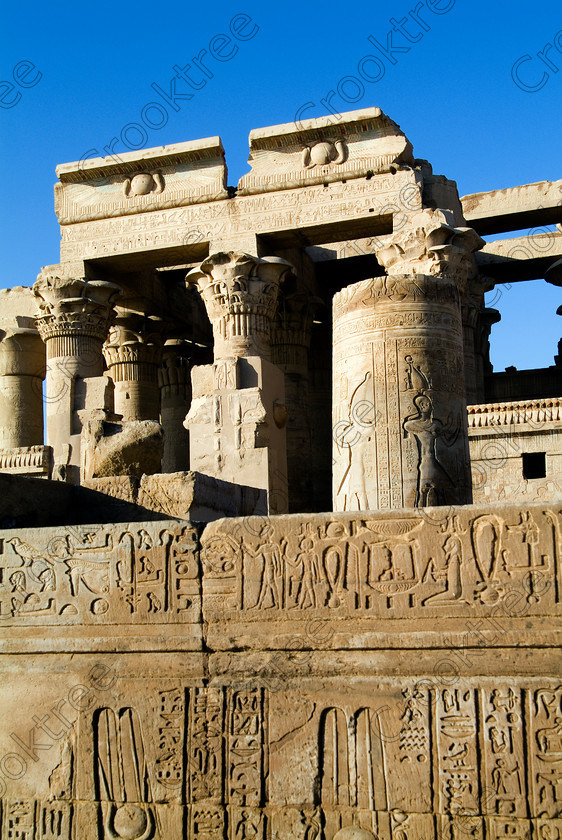 Kom Ombo Temple EG052517JHP 
 Ancient Egyptian Kom Ombo Ptolemaic Temple Forecourt Wall Detail Photo on the River Nile just north of Aswan and a regular visit on all Nile Cruises, was principally built by Ptolemy V of Silsilah sandstone. Dedicated to two Gods – Sobek, the crocodile and Horus, the falcon and although it has been damaged over the years, mainly through slipping into the River Nile and some structural damage owing to earthquakes, there are still some wonderful colourful reliefs of the most detailed and delicate style. 
 Keywords: Egypt, East Bank, River Nile, Kom Ombo, Temple, hypostyle hall, columns, bas reliefs, hieroglyphs, coloured, colored, colours, colors, Silsilah, sandstone, upright, history, archaeology, ancient, Egyptian, Egyptology, crocodiles, Ptolemaic, Ptolemy, Horus, Haroeris, Harwer, Sobek, Hathor, carvings, detailed, delicate, beautiful, fine