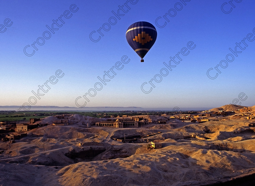 Luxor Balloon EG94211jhp 
 Balloon flight Luxor West Bank Metropolitan House Asasif khokha hill Egypt with the famous temple of Ramesses is located just beyond the hill line and is situated on the West Bank location of the Nile at Luxor. In this general area are several Tombs of the Nobles which are usually privately organised visits but very well worth the time if you have a few days to spare in Luxor. The balloon flight illustrated here was in 1994 and there were only two although in later years these increased greatly in numbers. This trip took off from the front of Hatshepsut just after dawn, a cold and interesting crossing of the Nile in the dark and long before the modern road bridge and eventually landed in the desert where the Hilton Hotel put on a beautiful breakfast buffet. 
 Keywords: Egypt, Egyptian, Luxor, Ramasseum, Temple, West, Bank, River Nile, Thebes, Qurnat, Murai, Shaykh 'Abd al-Qurnah, West, Bank, Khokha, hill, Metropolitan, house, domes, landscape, history, archaeology, ancient, Egyptology, hieroglyphics, granite, Osiride, statue, broken, Shelley, Ozymandias, pylon, court, columns, base, hieroglyphs, Ramses, Ramasses, Ramesses, glowing, golden, sunlight, dawn, agriculture, farming, houses, tombs, Nobles, high, panorama, balloon, balloons, high, flying, soaring, 1994, slide, film, 645, medium, format, transparency, scanned, scan, Bronica, ETRSi